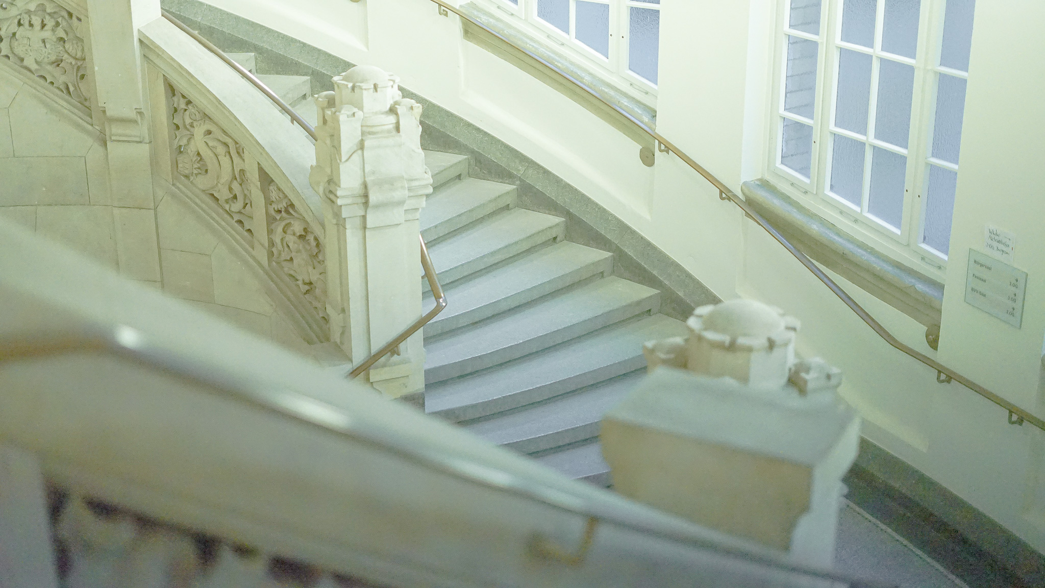 Gepflegtes, helles Treppenhaus in Berlin mit frisch geputzten Fenstern. Fachgerechte Glasreinigung durch das Reinigungsunternehmen Capital Infradienst GmbH für einen erstklassigen ersten Eindruck im Eingangsbereich